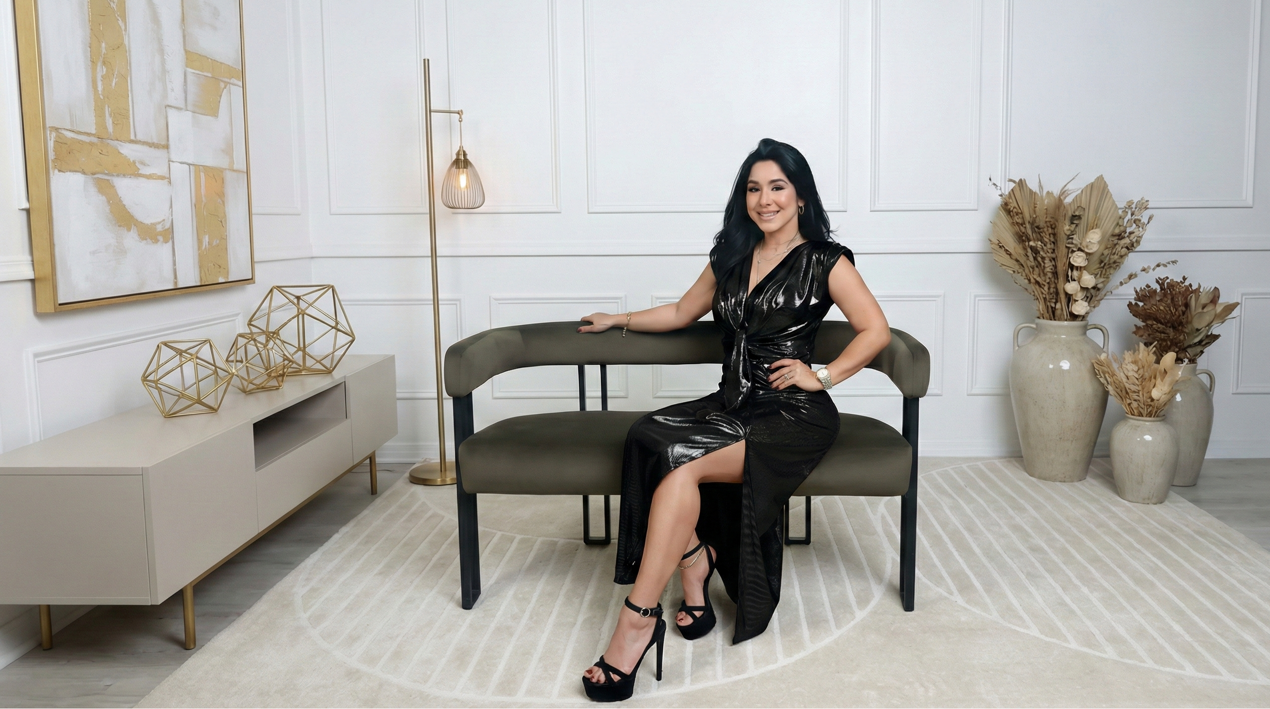 Woman in a black dress sitting on a modern chair in a stylish room with decor elements.